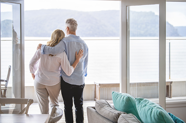 middle-aged couple hugging and looking out onto their lake-house view